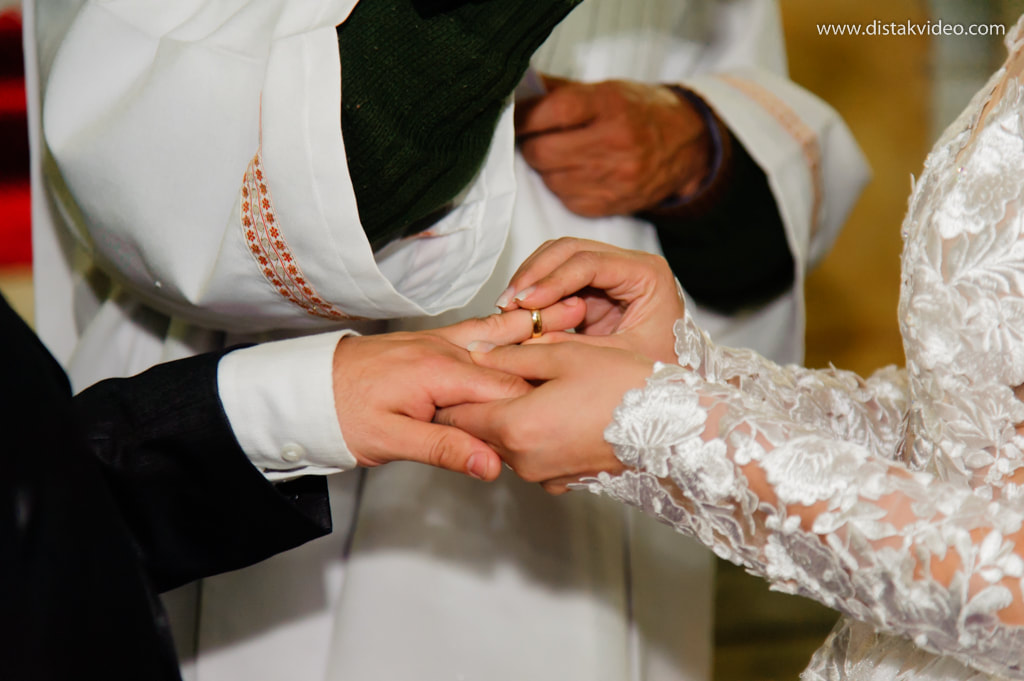 Noiva colocando alianças no noivo